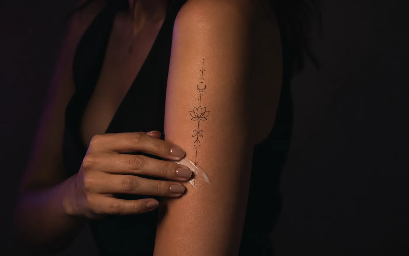 Tatuagem fineline de lótus no braço em cicatrização normal, com hidratante recém-aplicado