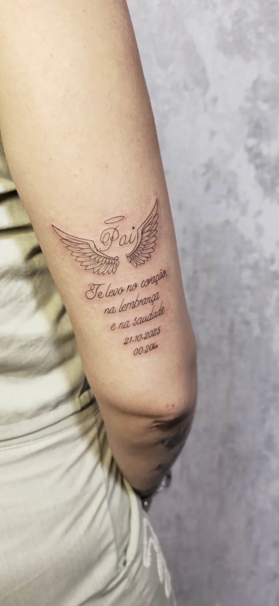Asas com lettering de homenagem no braço