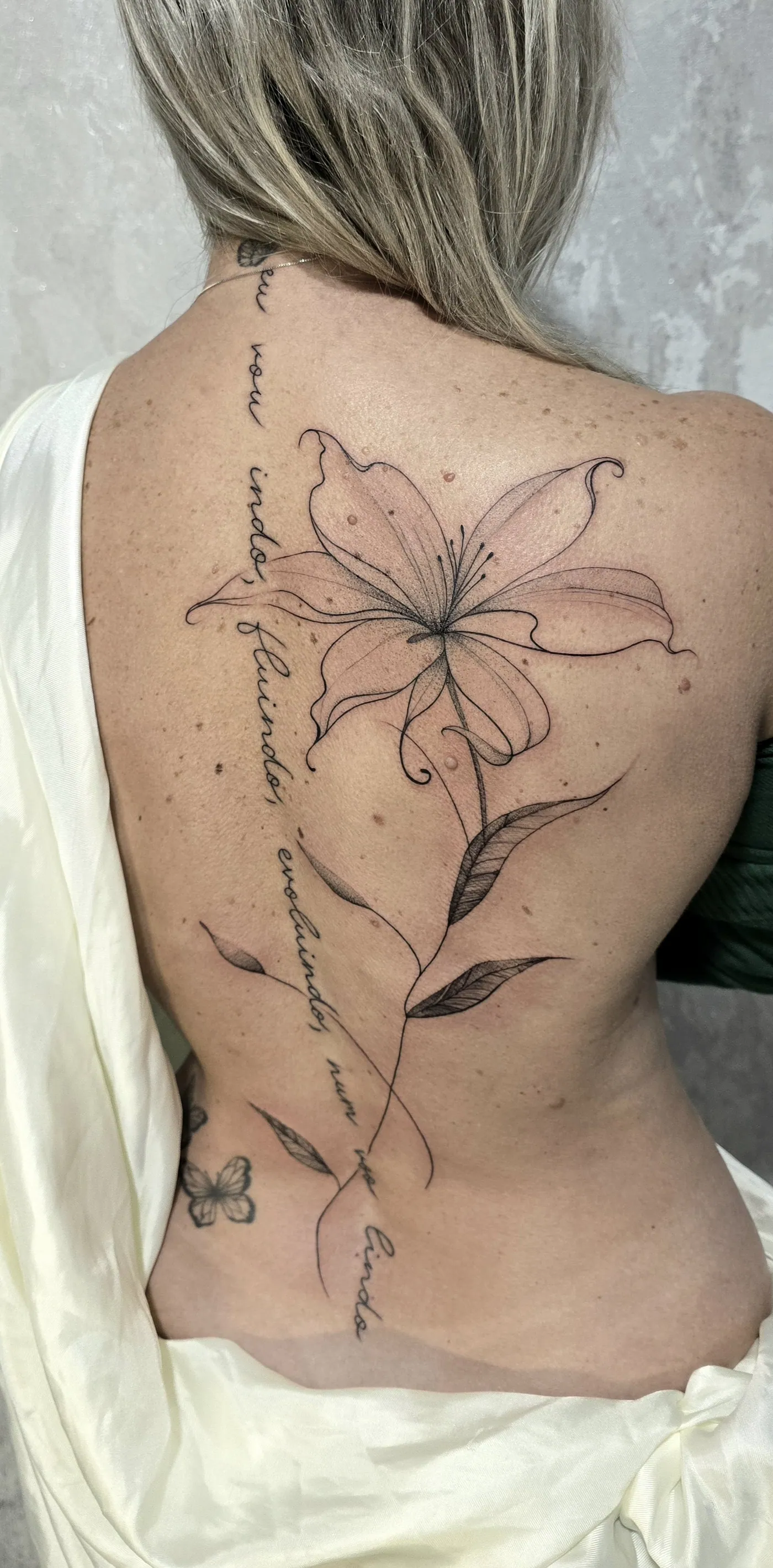 Lírio nas costas acompanhado de lettering