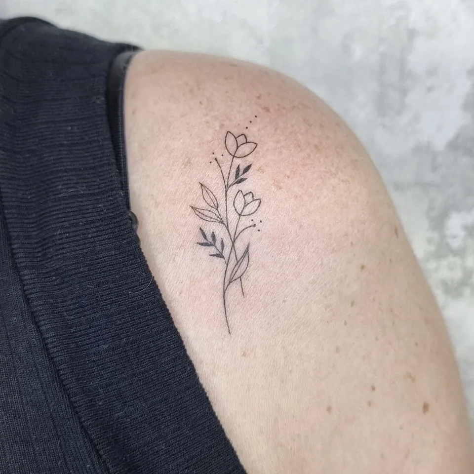 Flores minimalistas em traço fino no ombro
