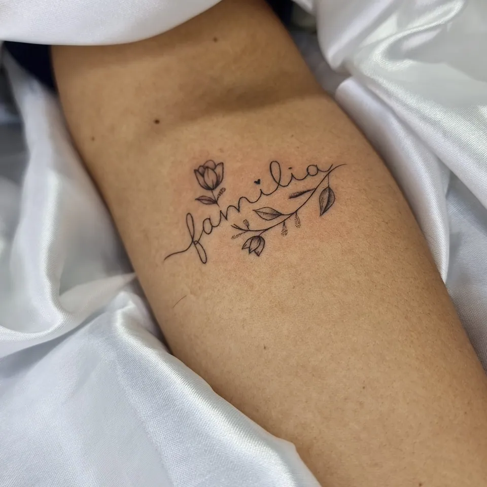 Palavra família com flor em traço fino no braço