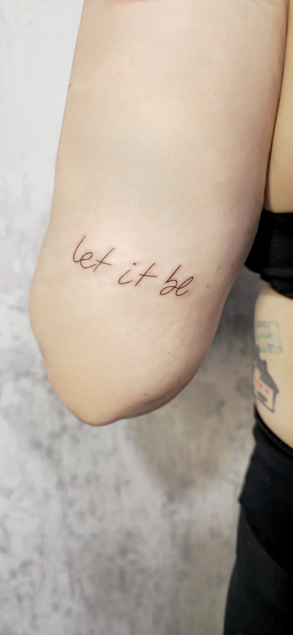 Frase em lettering cursivo no braço