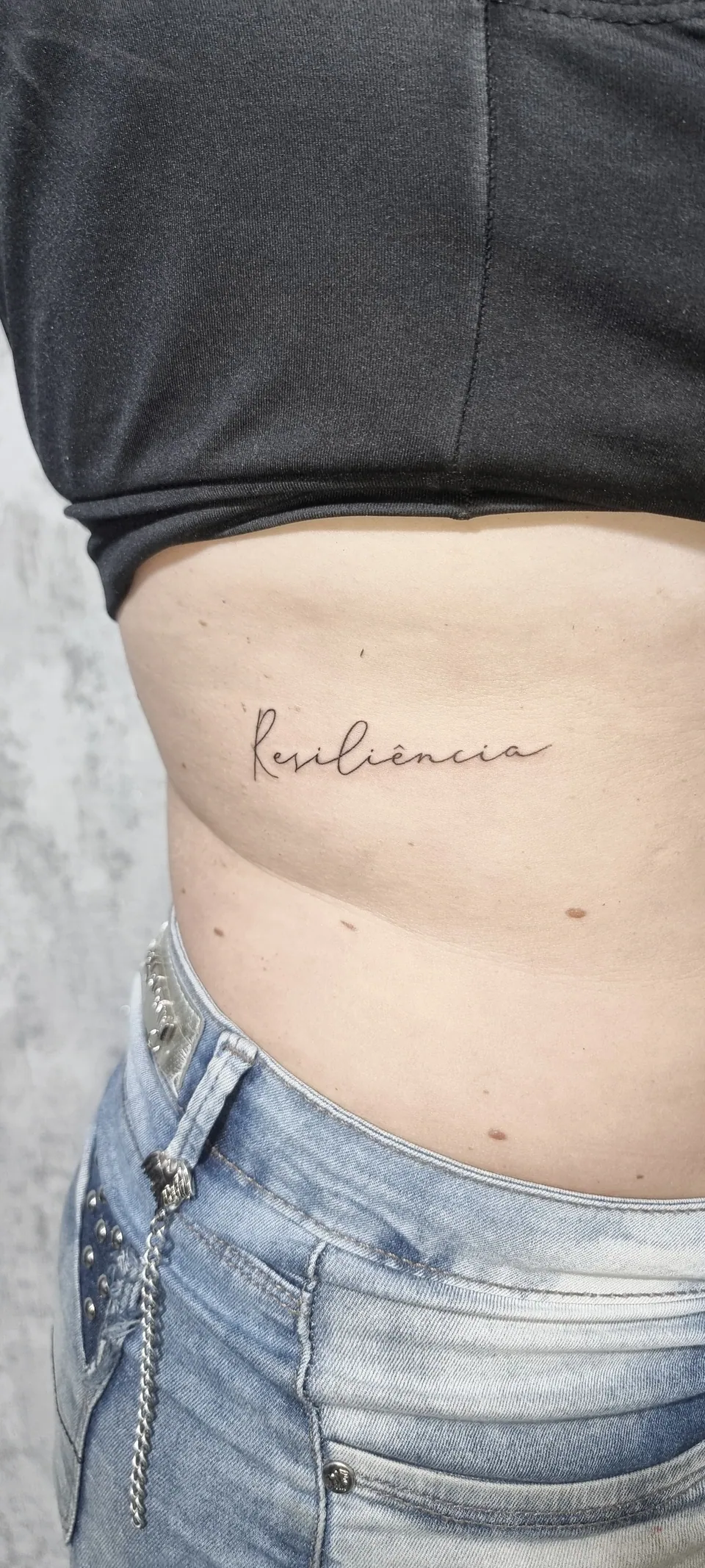 Palavra em lettering cursivo no abdômen